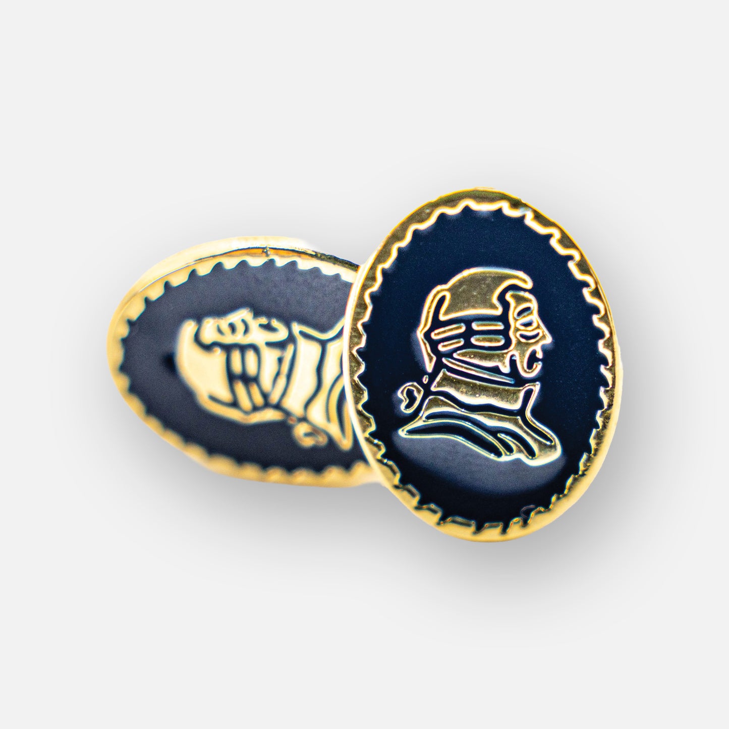 Two navy blue lapel pins with gold portraits.