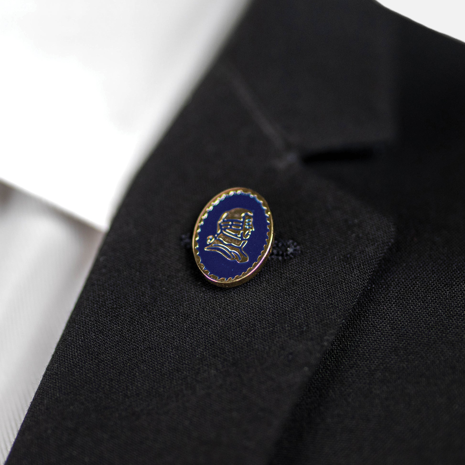 Blue and gold lapel pin on a black suit jacket.