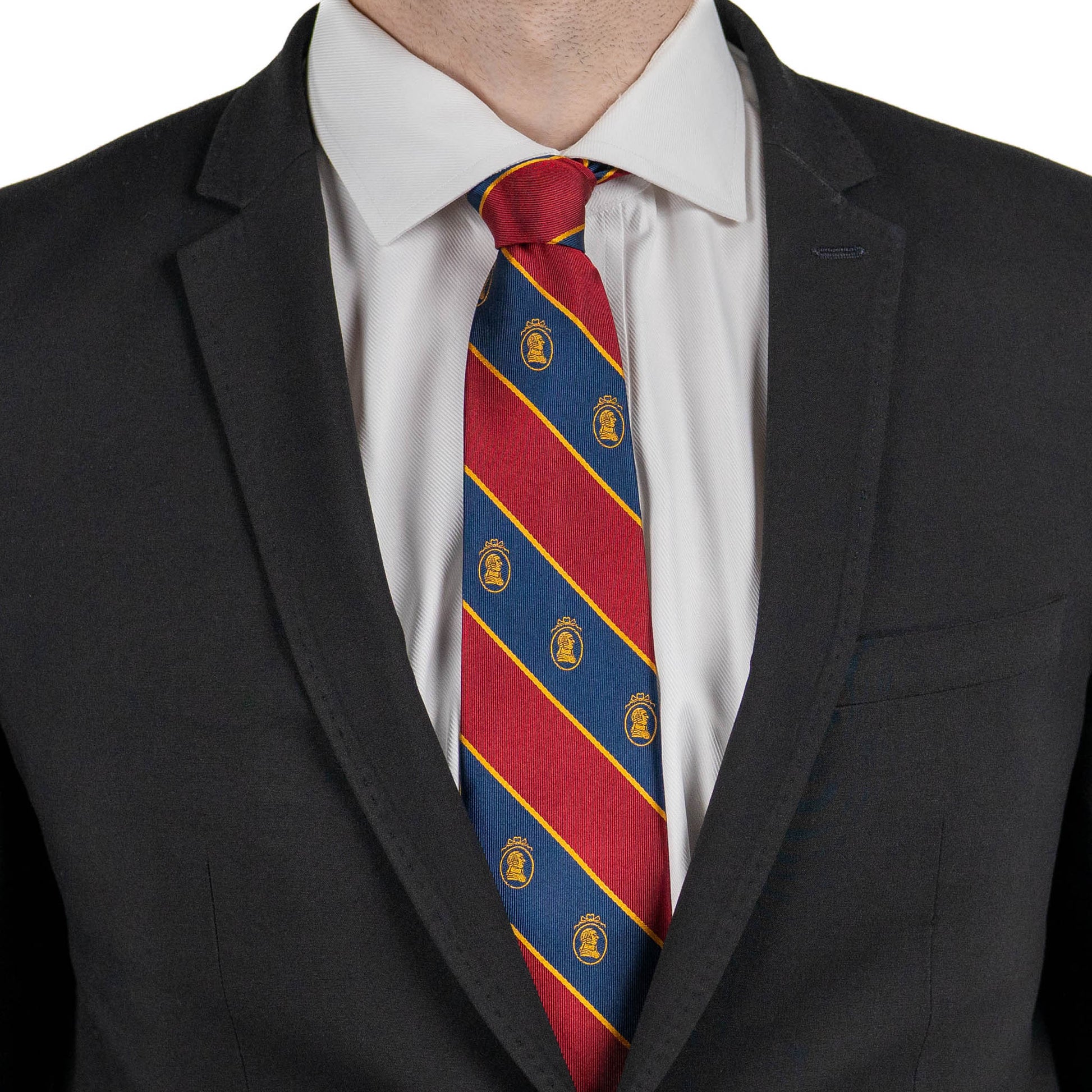 Person wearing a black suit with a red and blue striped tie featuring gold logos.